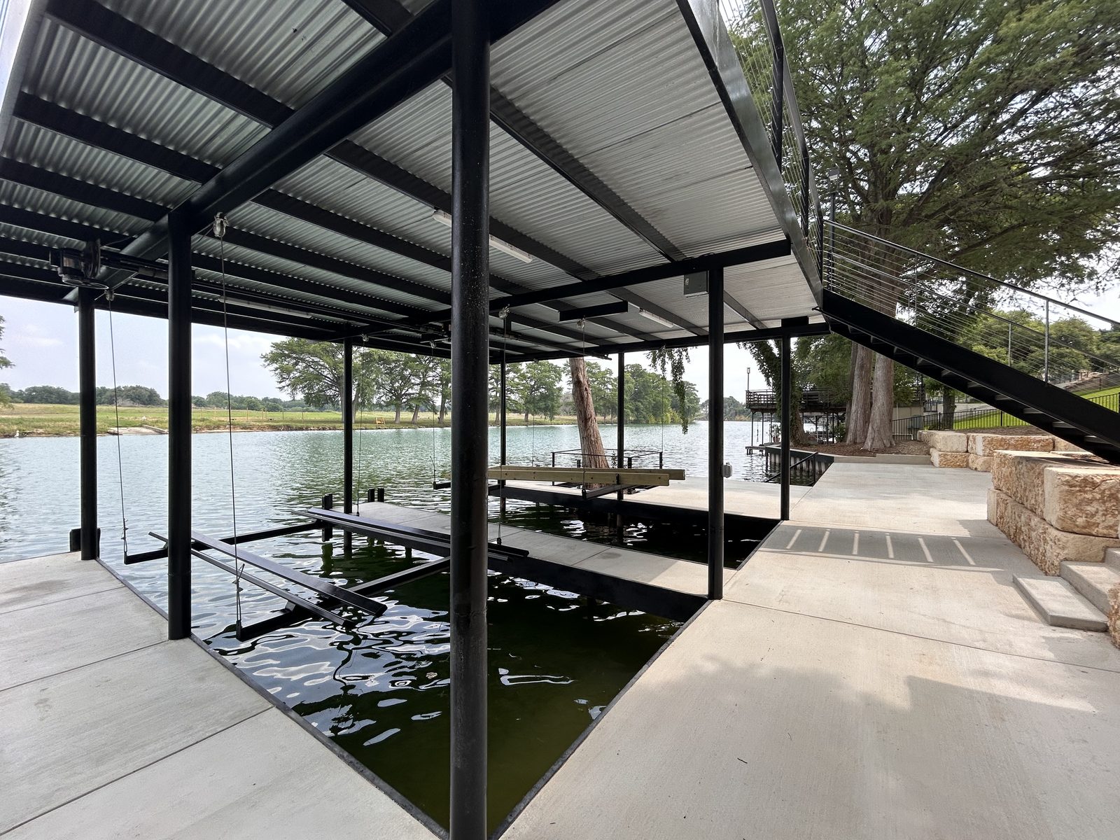Double boatlift boathouse with upper-level patio and retaining wall on Lake Dunlap by Waterfront Unlimited
